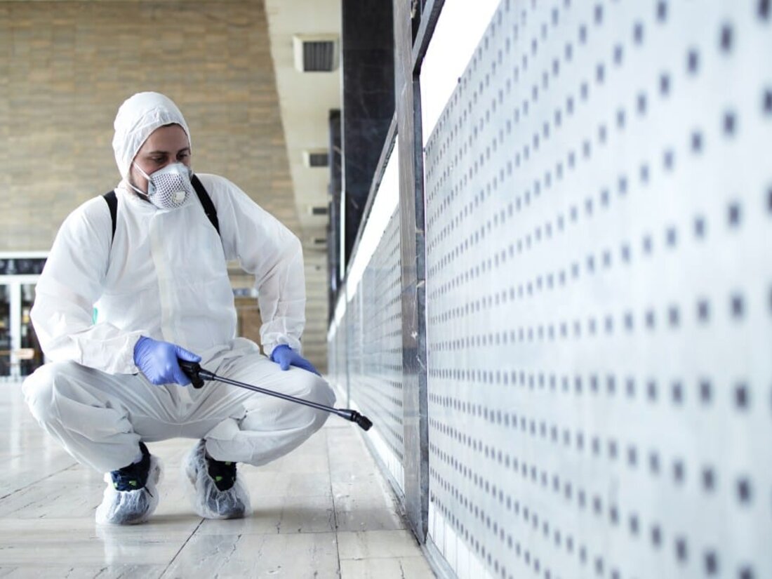 Técnico en traje de protección sanitizando un espacio con equipo profesional